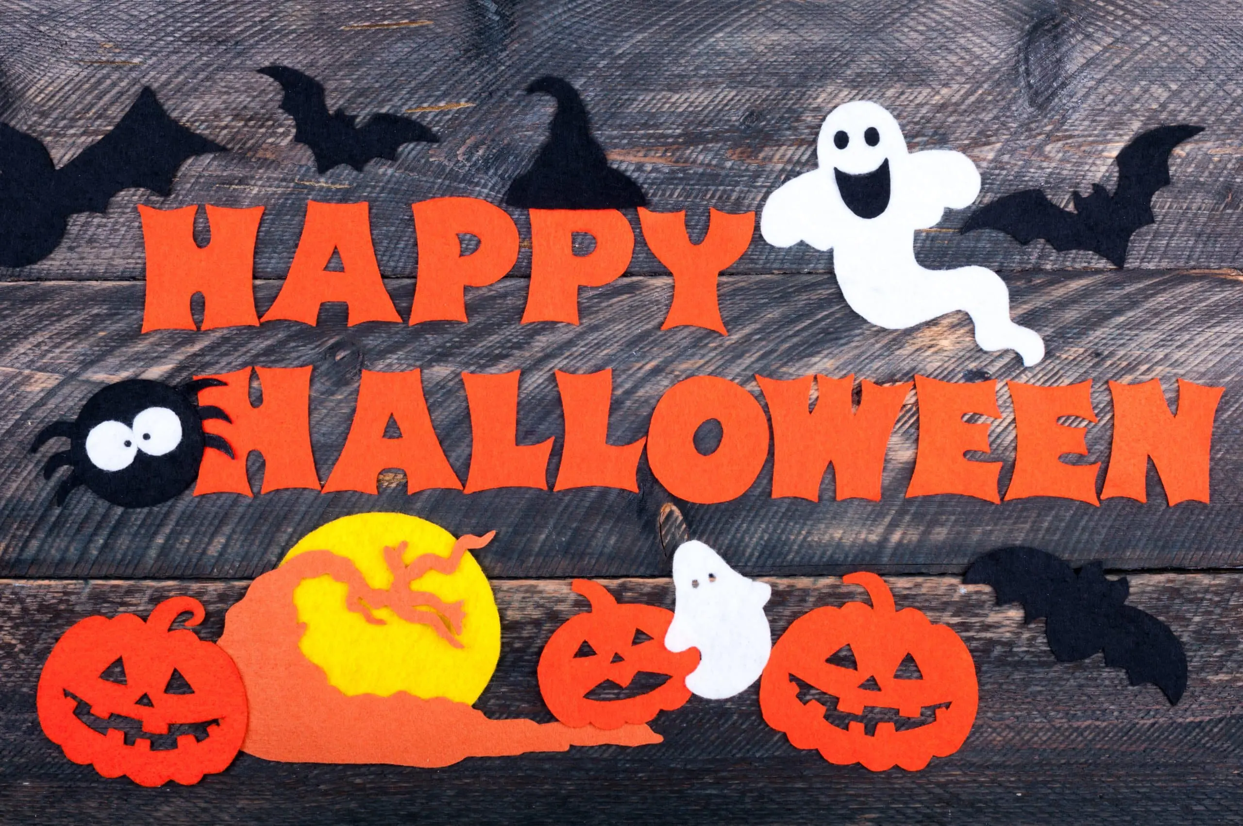 a group of felt pumpkins and ghosts on a wood surface
