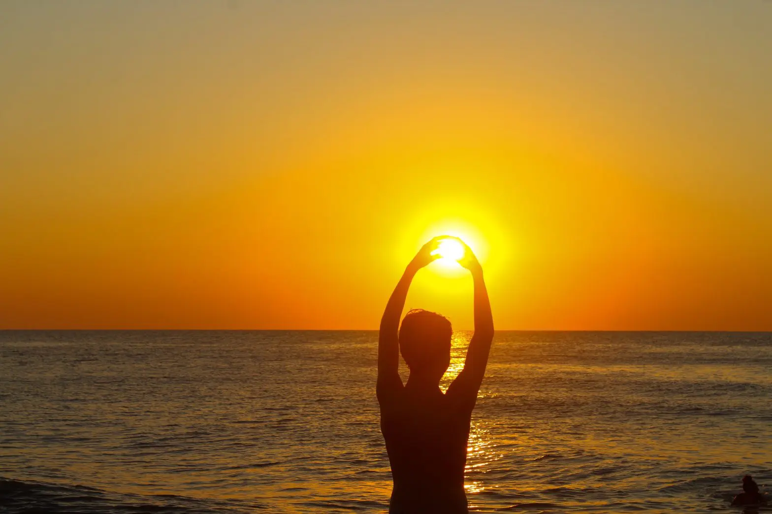 a person holding the sun above the water