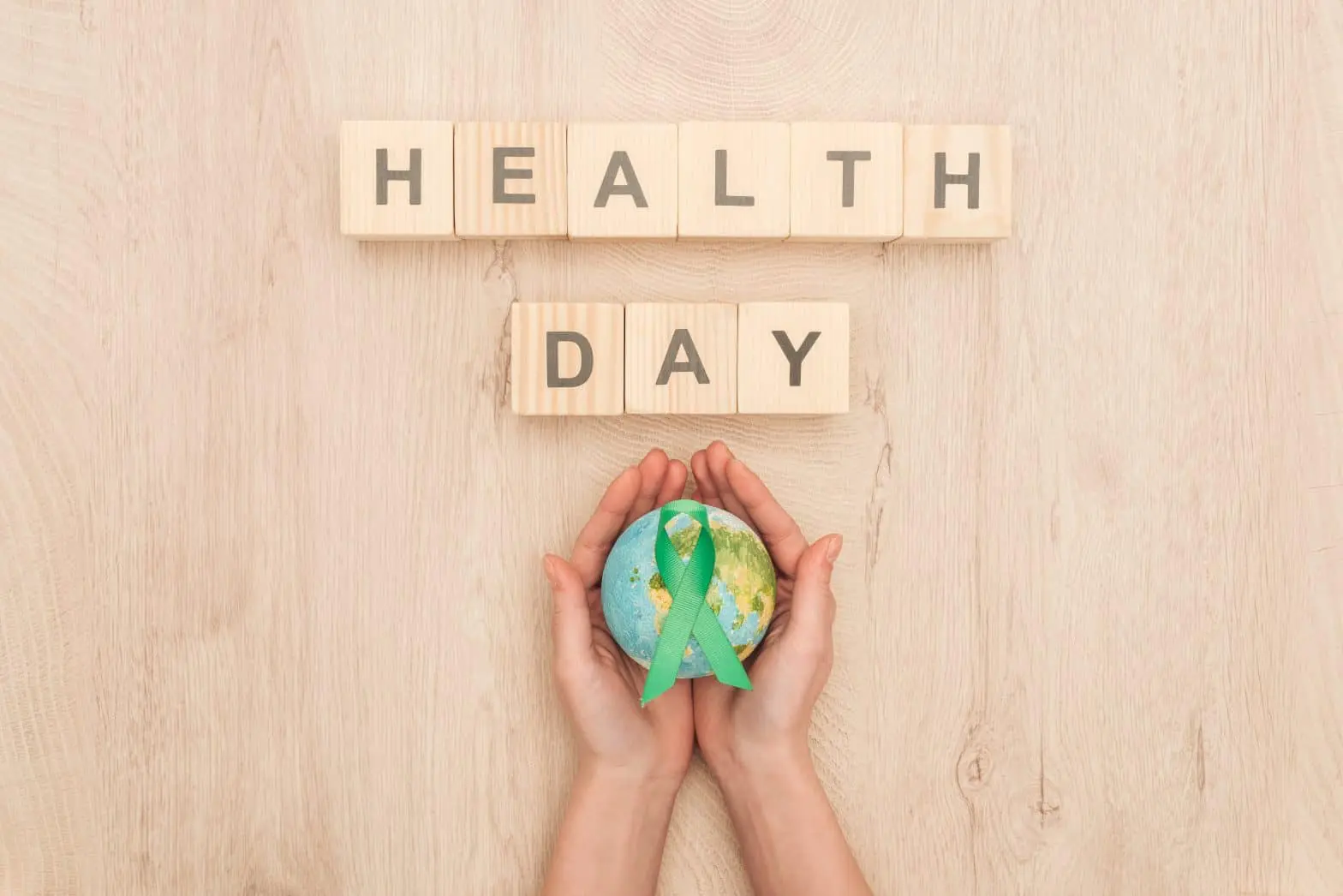a hands holding a globe with a green ribbon around it