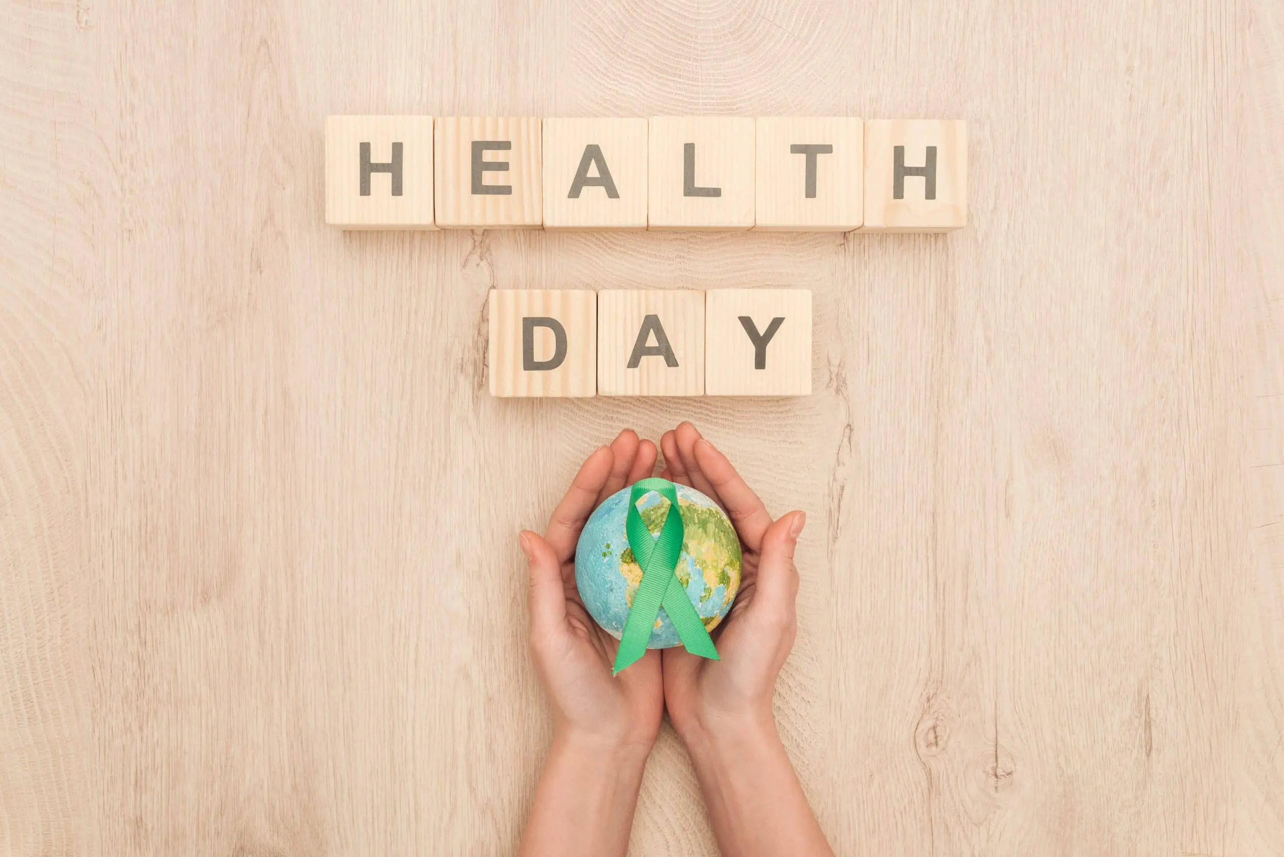 a hands holding a globe with a green ribbon around it