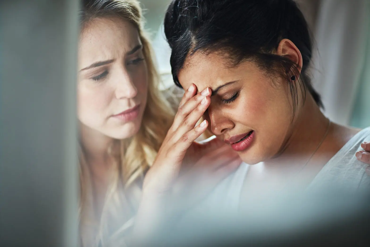 a woman holding her head with another woman