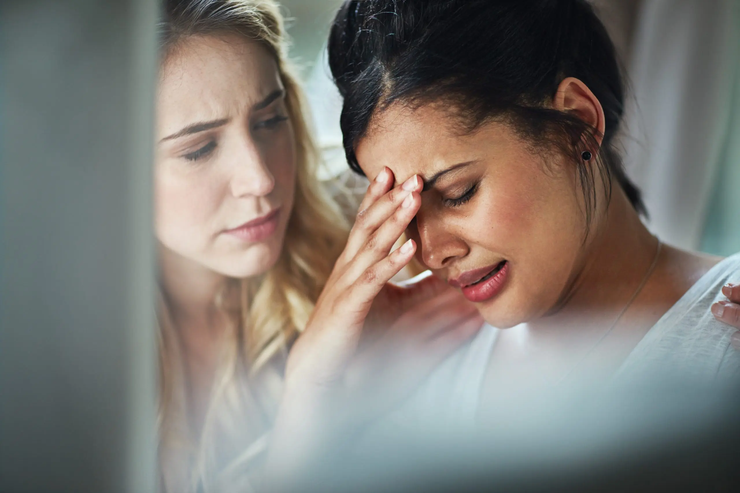 a woman holding her head with another woman