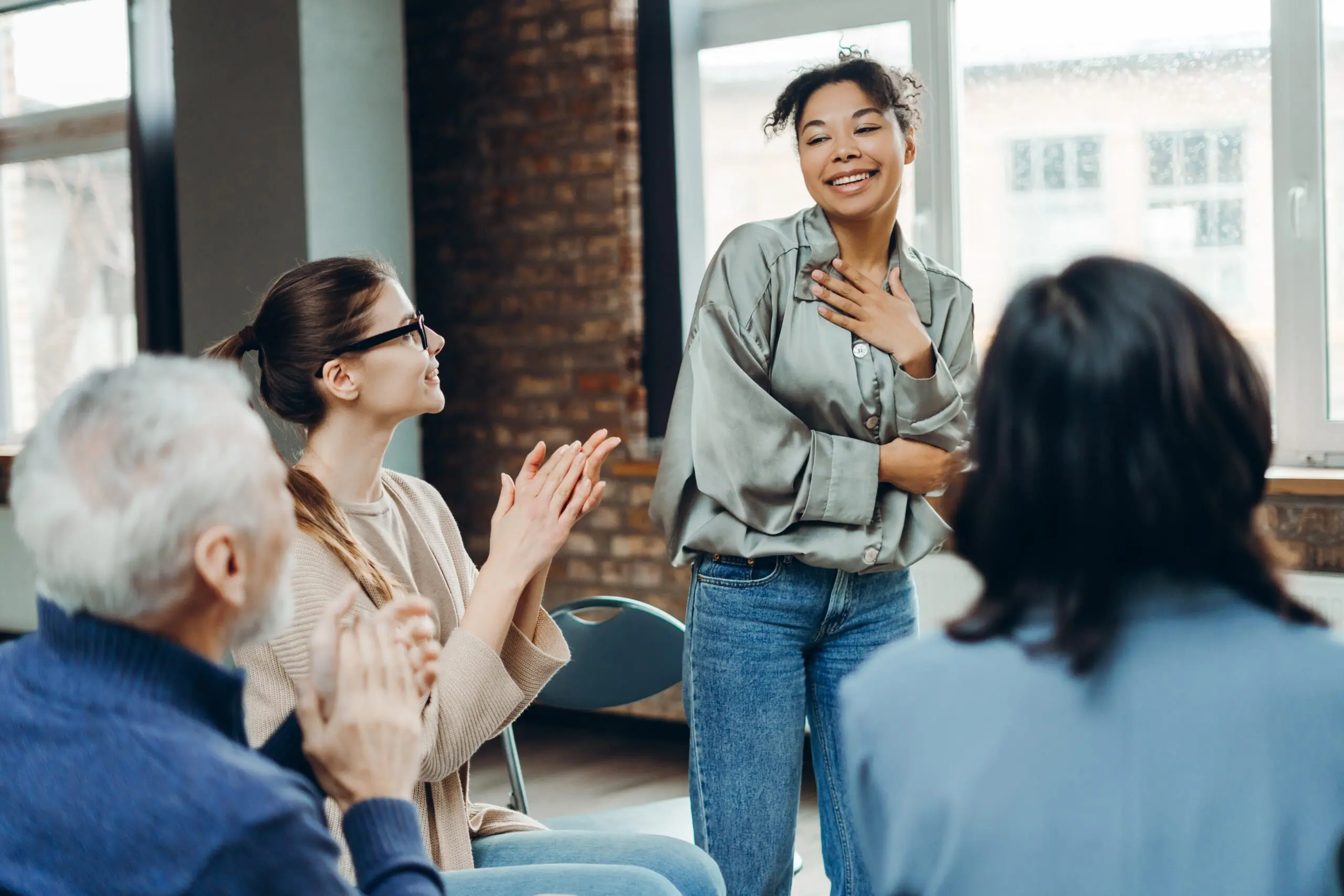 A group of people in a supportive recovery meeting smiling and connected scaled 5 Steps to Finally Overcome the Fear of Asking for Help
