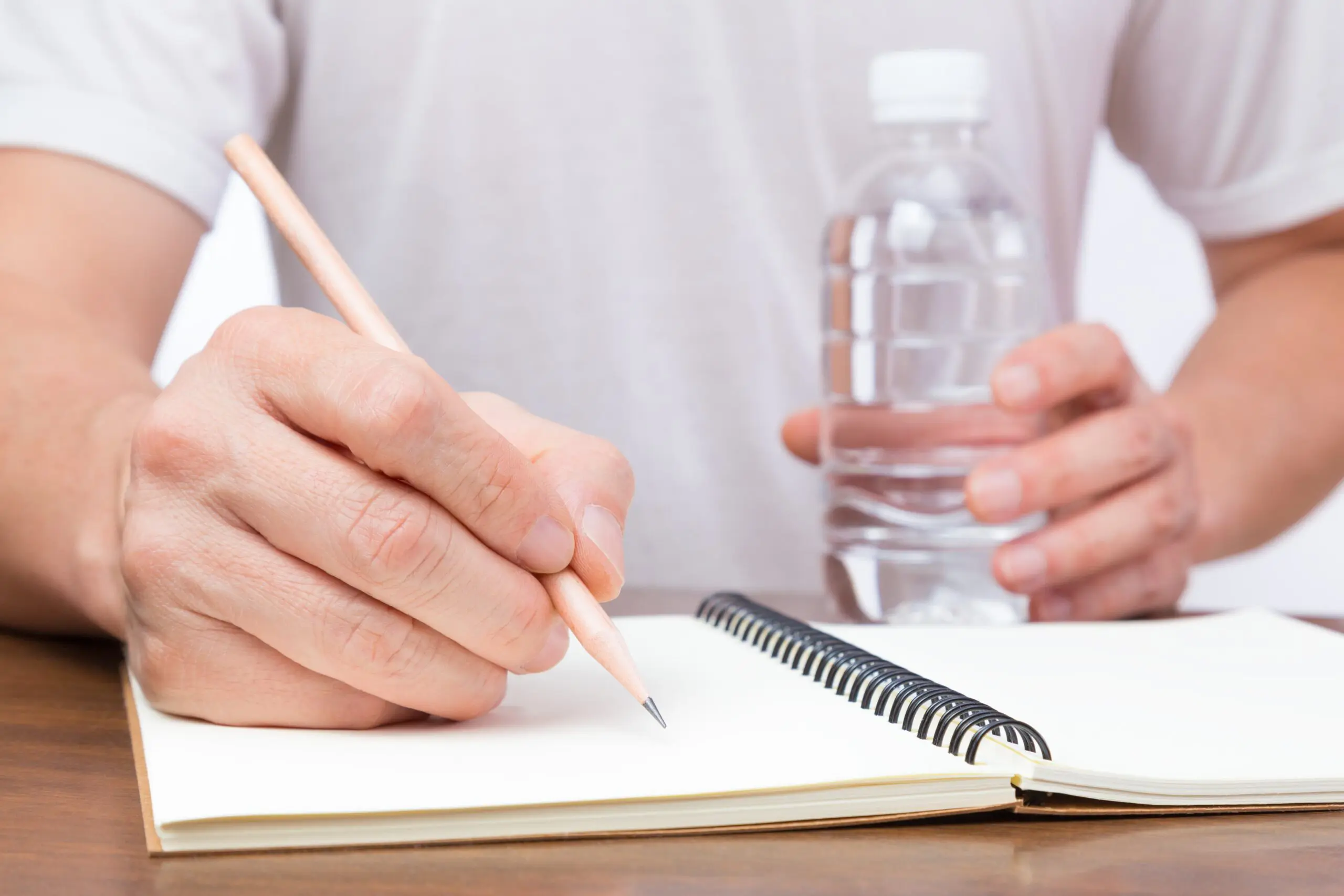Refillable water bottle placed on a table next to a recovery journal and supportive literature scaled Why Staying Hydrated Helps with Addiction