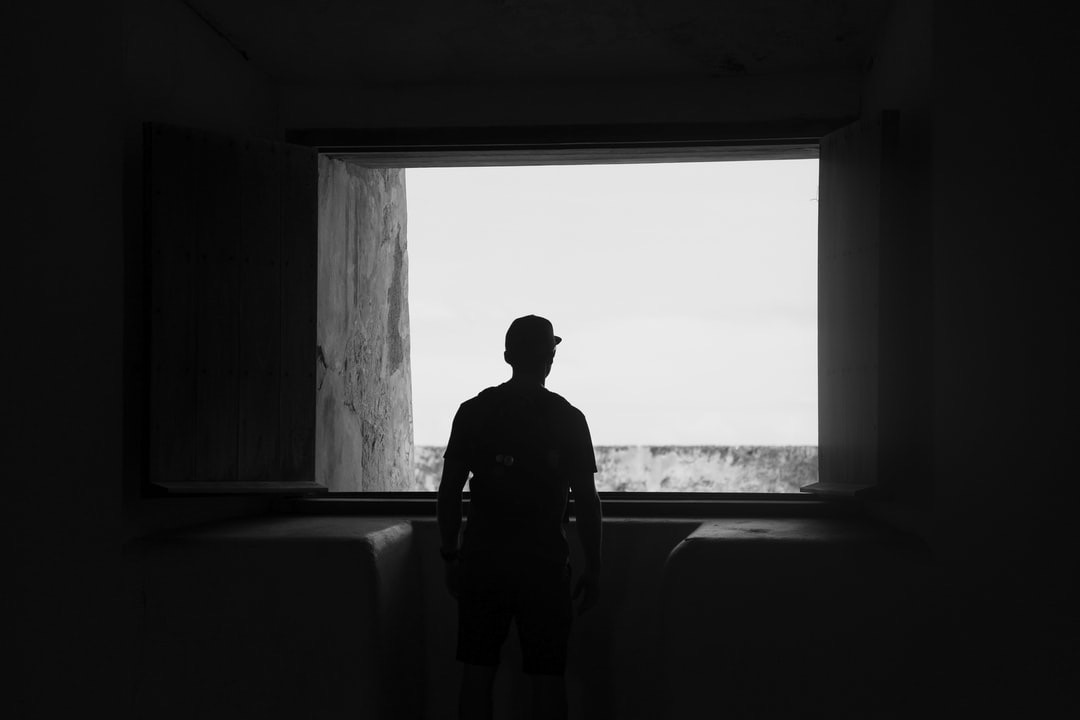 Young man looking out the window wondering if sobriety vs. recovery are the same thing