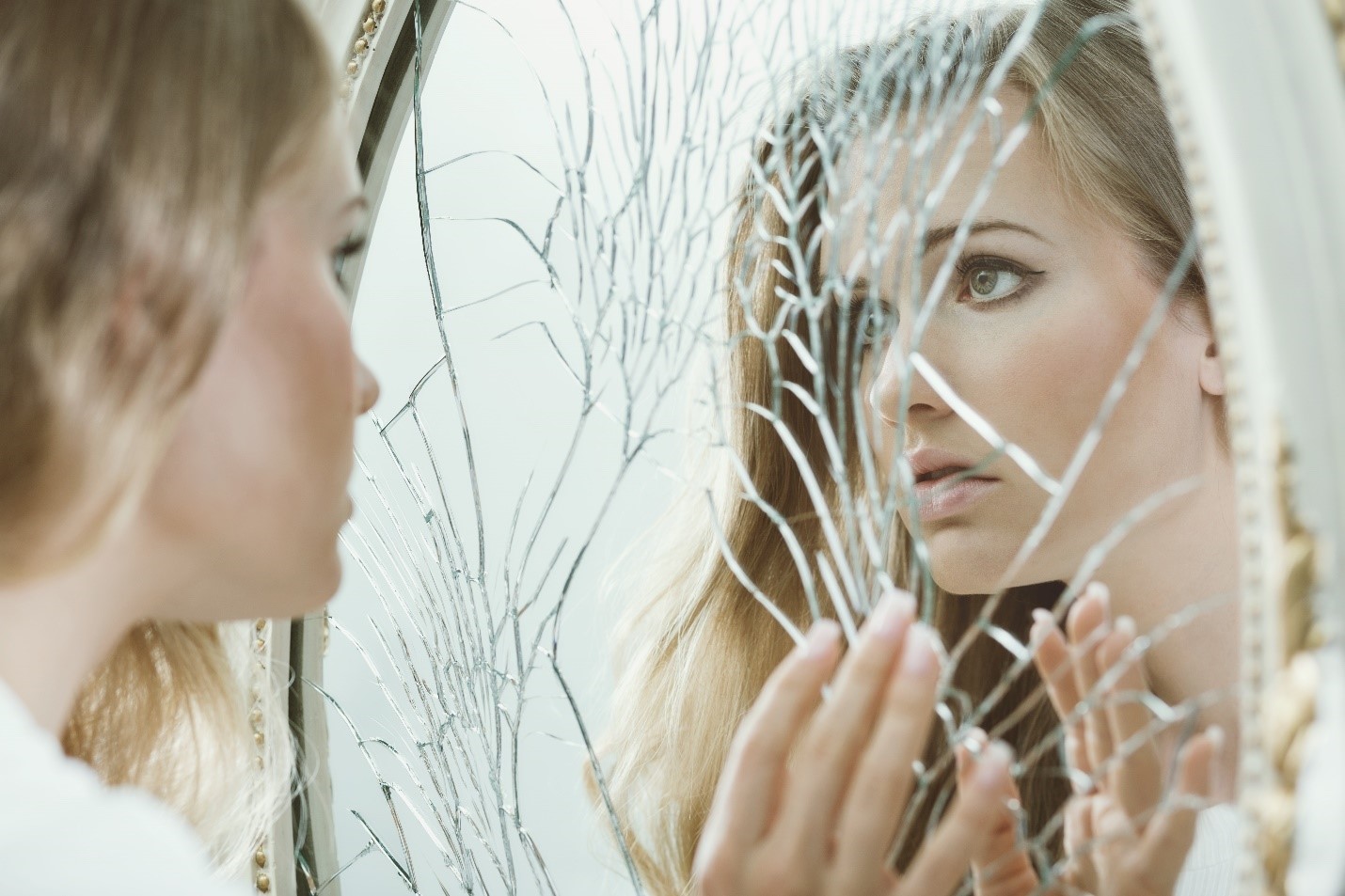 Teen girl front of a cracked mirror