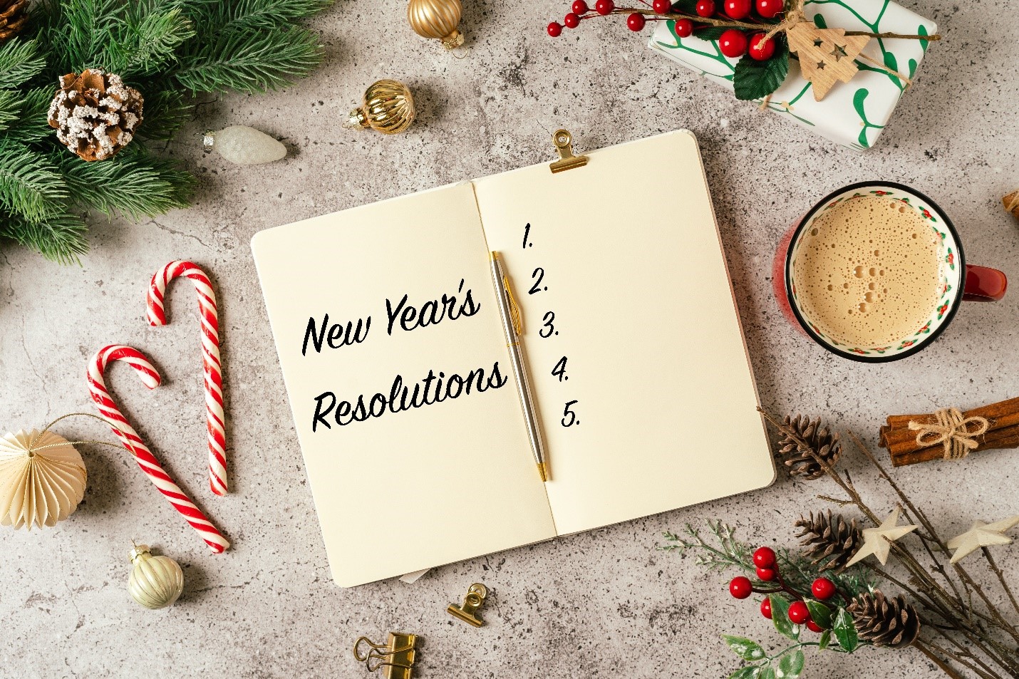 a book with New Year's resolutions written on it, surrounded by festive decorations