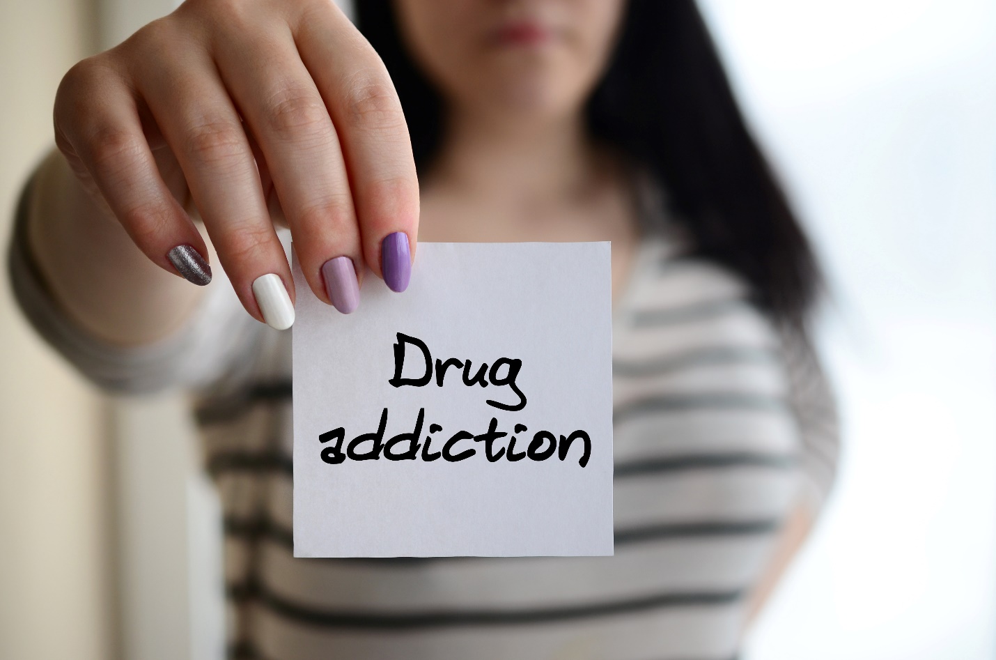 a woman holding a note that says "drug addiction"
