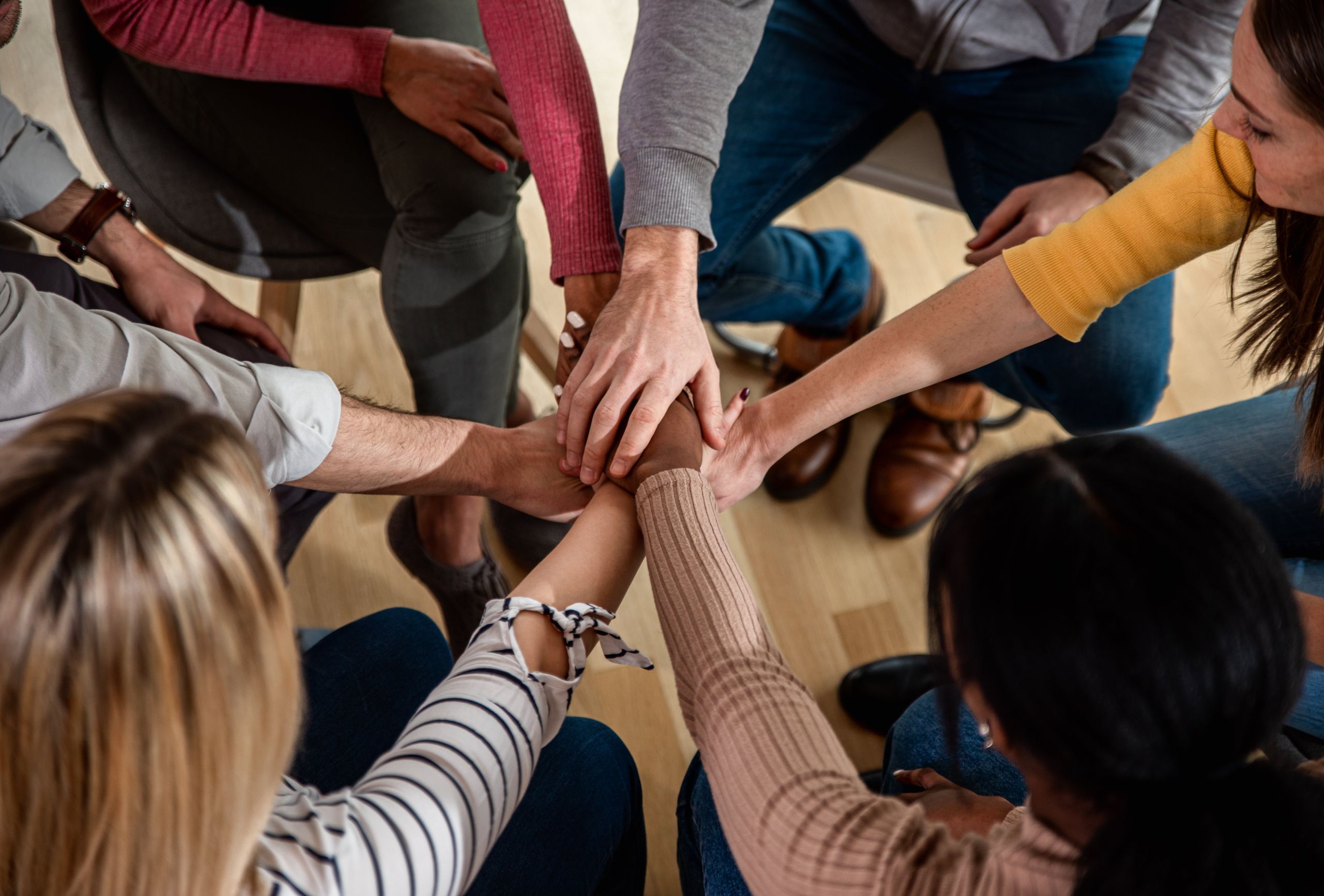 Diverse group of people holding hands circle in group therapy