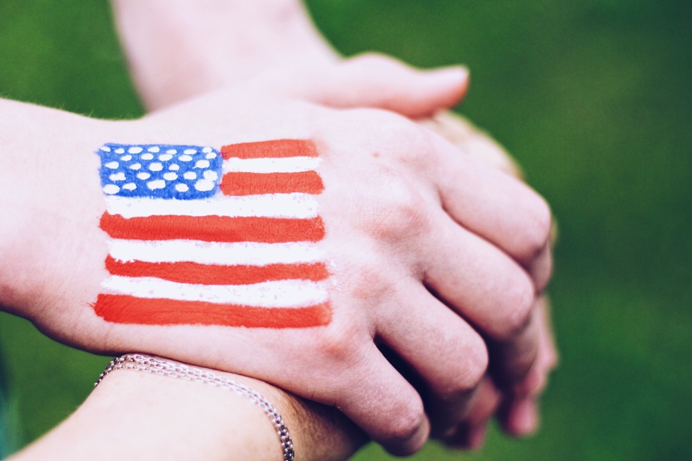 Hands clasping together with the American flag painted on them, showing the power of a sober 4th of July