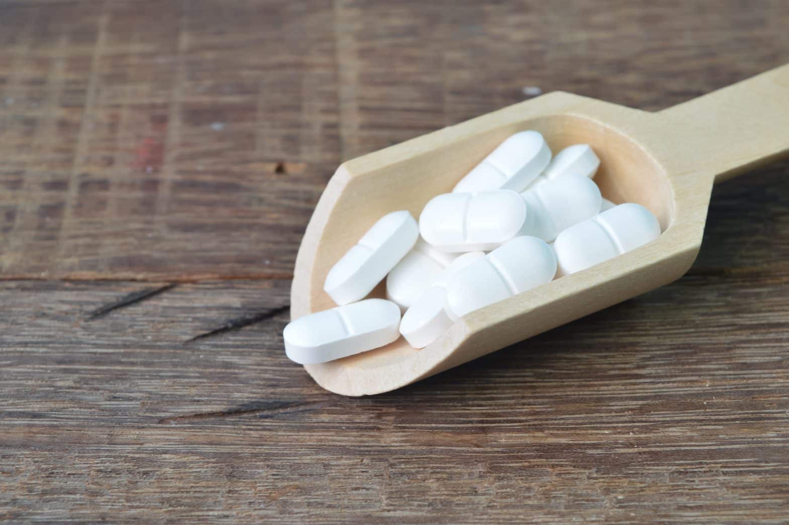 a wooden scoop full of pills