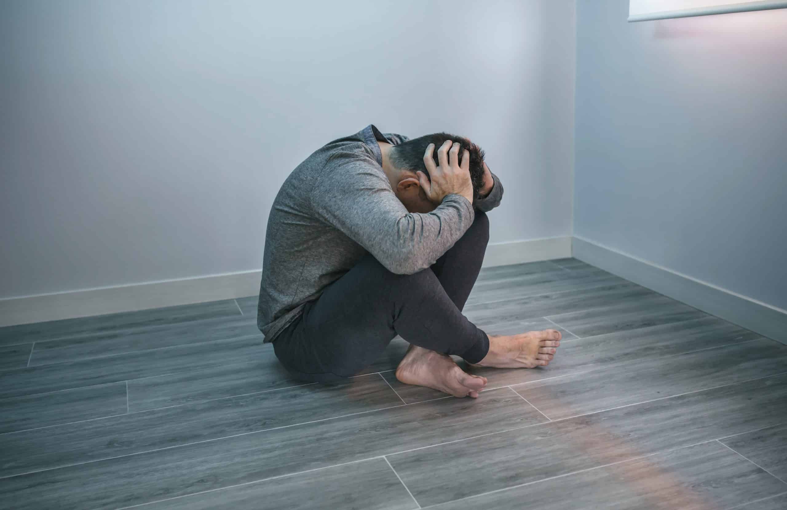 a man sitting on the floor with his hands in his head