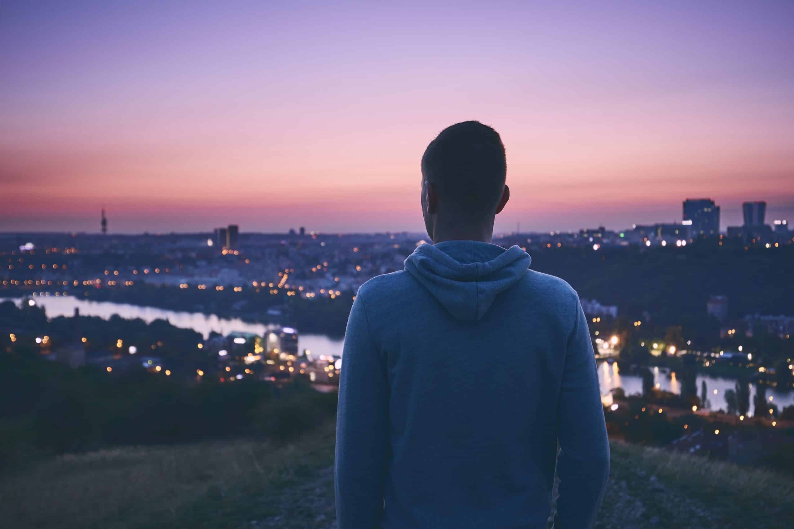 a man standing on a hill looking at a city