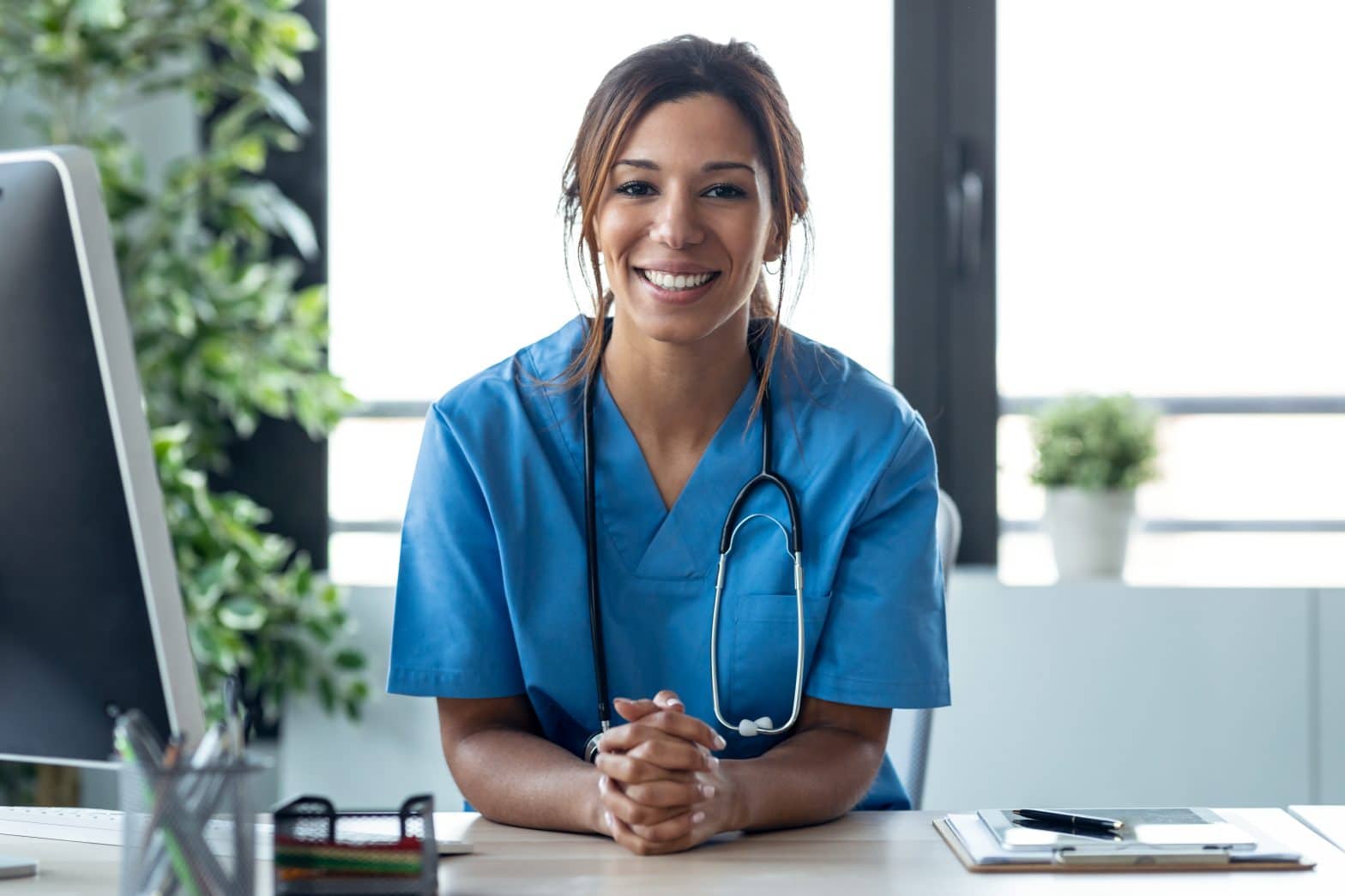 a woman in blue scrubs with a stethoscope around her neck