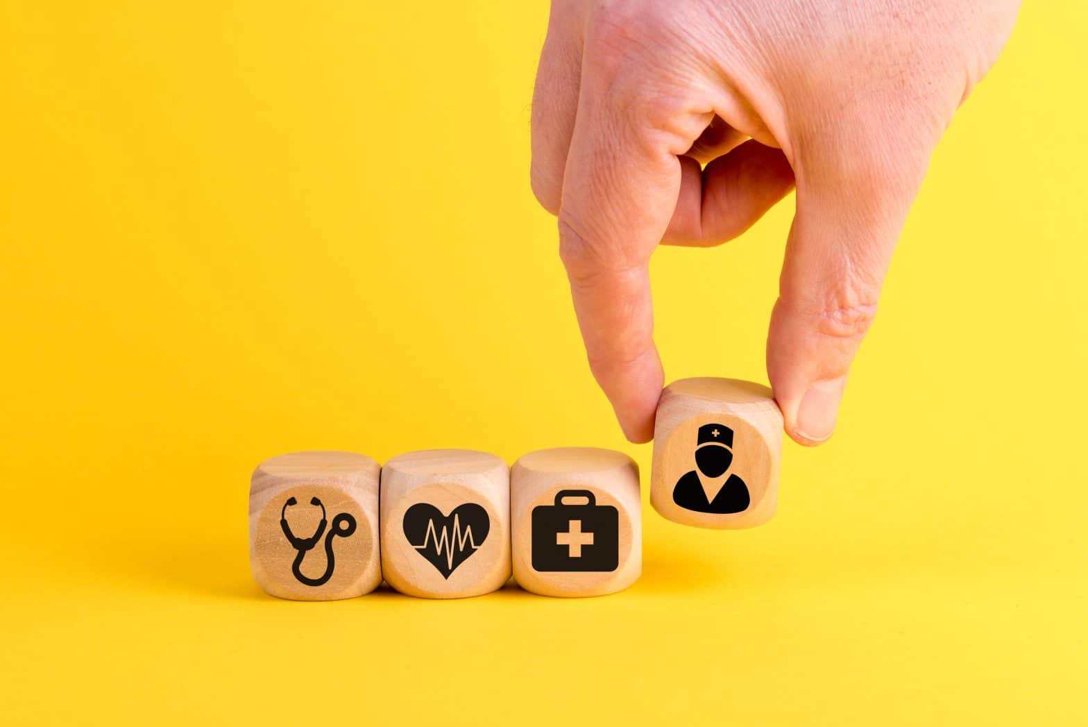 a hand placing a wooden cube with icons on it