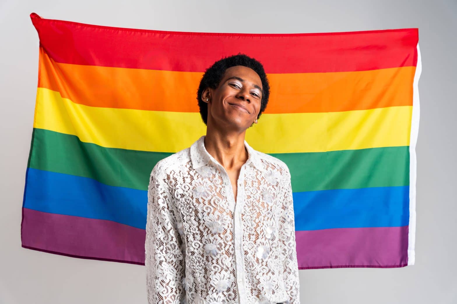 a man standing in front of a rainbow flag
