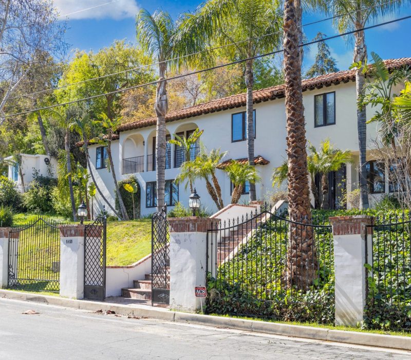 a white house with palm trees and a gate