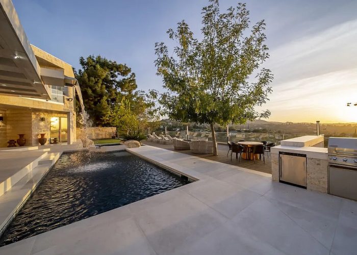 a pool and a house with a tree and a sunset