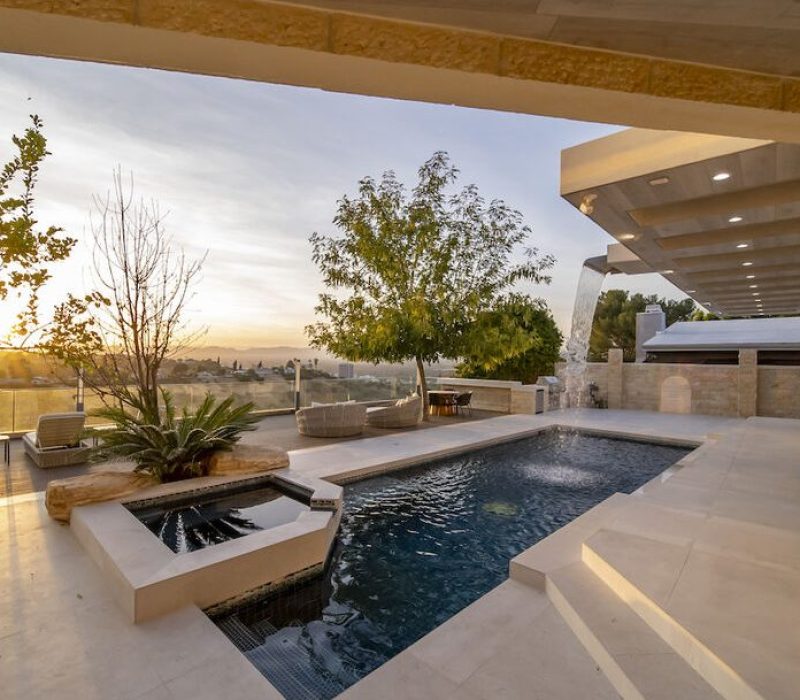 a pool with a fountain and a tree in the back
