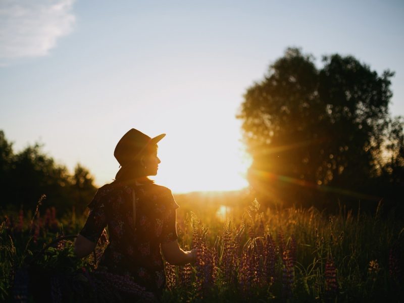 a woman in a hat in a field of flowers